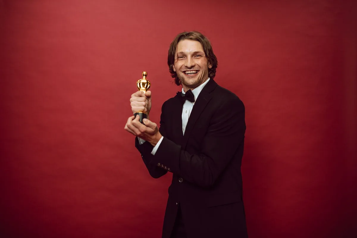 Gala ceremony with silhouetted guests applauding as an award winner stands on stage holding a golden statuette